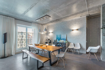 Stylish interior of a showroom in a loft-style room. Table and bench made of a single piece of wood.