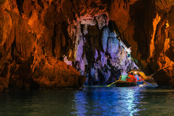 Tourists in boat navigating through cave of Tam Coc National Park in Ninh Binh, Vietnam