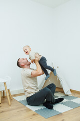 In a cozy living room, a father and his baby share joyful laughter while engaging in playful activities that strengthen their bond and create lasting memories of love and happiness
