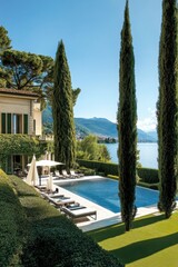 Fototapeta premium Luxurious villa overlooking a serene lake, featuring a pristine swimming pool and beautifully manicured gardens during a sunny afternoon in a picturesque landscape