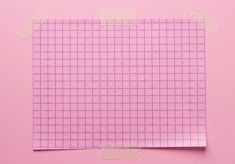 Pink grid paper taped on a pink background, minimal style.