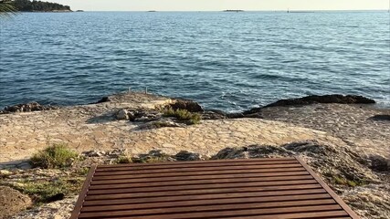 Two wooden loungers placed side by side on a rocky shore, ideal for a couple enjoying a peaceful seaside retreat. - Powered by Adobe