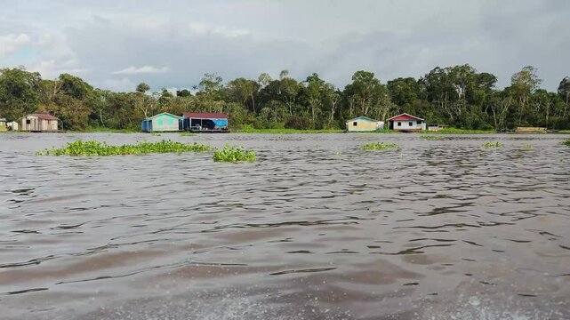 Wooden houses and trees during the flood in the amazon rainforest. Floating houses of riparian community. Black river. Negro river. Manaus, Amazonas, Brazil. 4K