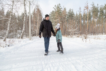 Dad and daughter walking and having fun in snowy winter forest