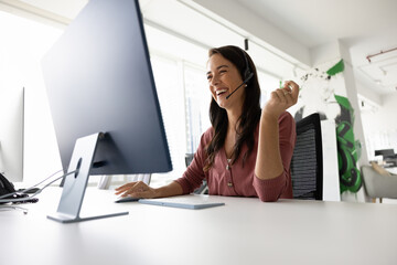 Funny teamwork online. Laughing young woman manager executive in digital earphones with mic having...