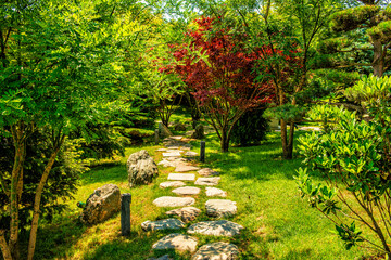A public park with dense ornamental vegetation and a cobblestone path