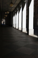 Long architectural tunnel with white columns connected by arches, illuminated by soft natural light...
