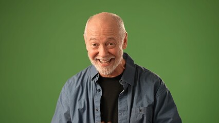 A senior man stands in front of a green screen, looking concerned as he holds a letter, conveying a range of emotions in a thoughtful moment.