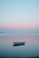 Naklejka premium Boat on the lake in the sunset with reflection in the water
