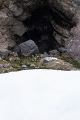 Cave with a stream flowing out and a mossy rock