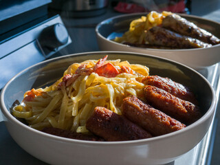 Hearty pasta swirling with crispy bacon studded sausages, steaming and glistening in ceramic bowl, embodying rich italian culinary comfort