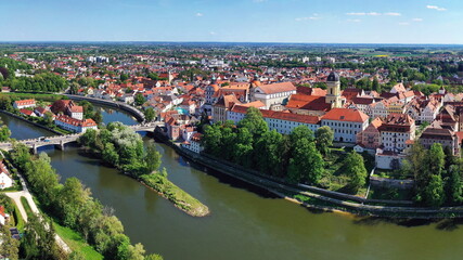 Eine beeindruckende Luftaufnahme von Neuburg an der Donau, einer malerischen Stadt in Bayern, Deutschland. Die Donau schlängelt sich durch die Stadt und bildet eine kleine Insel.