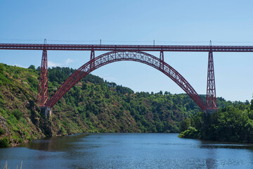 Red metal Garabit Viaduct over a river in France