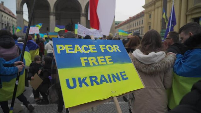 Inscription on blue yellow poster Peace for free Ukraine during demonstration against war in Ukraine at Odeonsplatz in Munich, Germany. Meeting banners and placards protesting about war in Ukraine. 