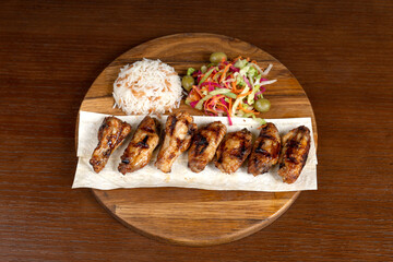 Fried chicken wings and legs, Turkish rice, mixed salad on the restaurant table on a wooden stand