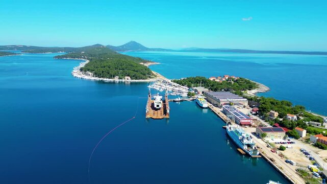 Daytime aerial view of Mali Lo&scaron;inj (Losinj), Croatia, featuring Župna crkva rođenja Blažene Djevice Marije and charming coastal architecture along the Adriatic Sea. A peaceful and sunny island scene