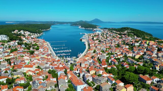 Daytime aerial view of Mali Lo&scaron;inj (Losinj), Croatia, featuring Župna crkva rođenja Blažene Djevice Marije and charming coastal architecture along the Adriatic Sea. A peaceful and sunny island scene