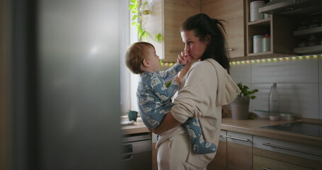 Fototapeta na wymiar Mother smiling at baby in kitchen, casual parenting and bonding moment during warm family morning routine, home life with nurturing and love