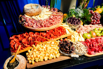 table of cold cuts, nuts, fruits, and cheeses at a food station at a party