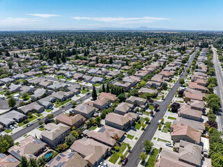 Aerial view of a suburban residential neighborhood in Stockton, California, showcasing rows of single-family homes, streets, and surrounding farmland. Ideal for topics related to urban planning, Calif