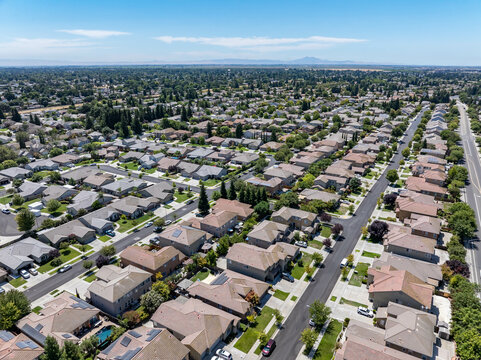 Aerial view of a suburban residential neighborhood in Stockton, California, showcasing rows of single-family homes, streets, and surrounding farmland. Ideal for topics related to urban planning, Calif