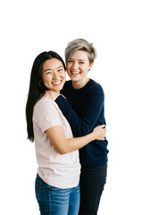 Fototapeta premium Two happy young adult women, one Asian with long dark hair and one Caucasian with short silver hair, smiling and affectionately hugging each other in a studio portrait with a transparent background.