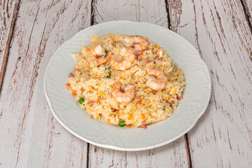 A freshly prepared plate of shrimp fried rice on a white wooden table