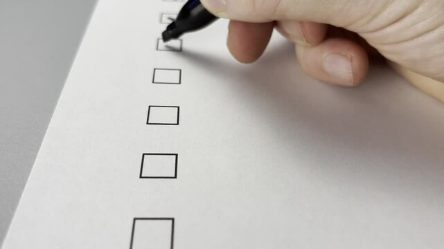 Close up of a check mark being written in a box with a black marker pen.