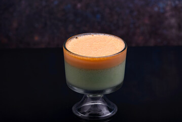 Cup with two colors foamy gelatin isolated on dark background