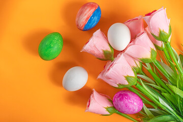 Bright spring flowers and colorful Easter eggs on a vibrant orange background.