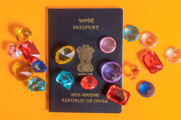 Indian passport surrounded by colorful gemstones on a bright orange surface