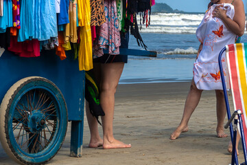 Peruibe, SP. April 12, 2009. Women choose beachwear from a street vendor's cart on the sands of a...