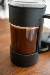 Brewing and pouring coffee with black french press on table in close-up