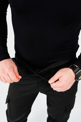 A person is seen adjusting the waistband of their black cargo pants while wearing a laidback...