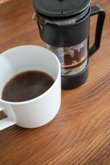 Brewing and pouring coffee with black french press on table in close-up