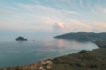 As the sun sets over Zakynthos, Greece, warm hues reflect on calm waters, perfect for serene contemplation and capturing the island's enchanting coastal landscapes