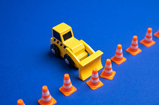 A yellow bulldozer pushes back a boundary of cones. The concept is to expand what is permitted, remove restrictions and rules. Idea of expanding freedom, lifting regulations, or redefining boundaries.