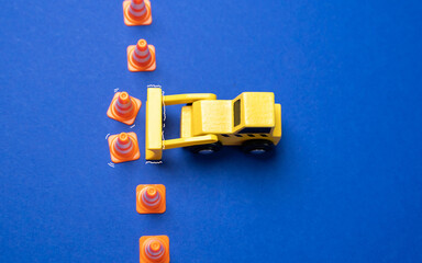 A yellow bulldozer crosses the line of cones. The concept of crossing boundaries and removing restrictions. Revision of norms and rules. Breaking through set norms, pushing past limitations