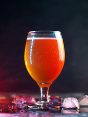 Cold beer glass in drops of water on table with ice cubes