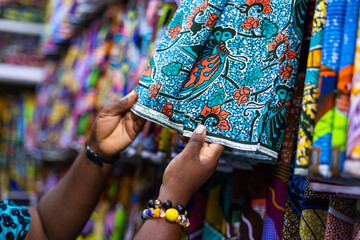 Small business owner of an African Print, Ankara fabric shop proudly displaying textiles prints.