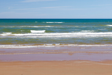 Soft wave of blue ocean on sandy beach in summer season. Prince Edward Island, Canada