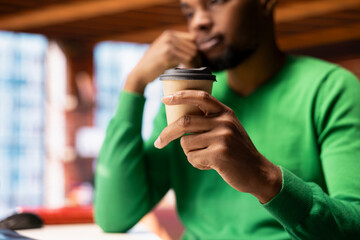 Man in home office drinking coffee in the morning and browsing internet, researching information. Teleworker starting job shift with hot beverage, preparing to do work tasks