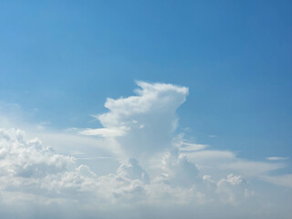 There are white cumulus clouds in the blue sky, one cloud looks like a running rabbit with ears