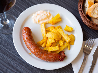Fried sausage butifarra and potatoes are complemented with bowl with hot sauce garlic-olive alioli. Traditional Spanish dish, gastronomic novelties and discoveries.