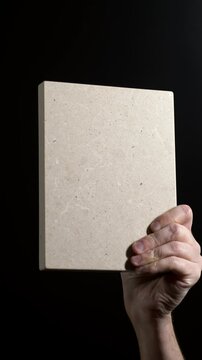 Luxury quartz stone texture pattern with trendy curly veins. Marble slab in hand on black background in Slow motion