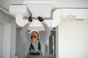 hvac services indian worker install ducted pipe system for ventilation and air conditioning in house