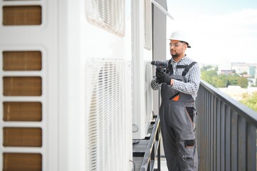 Indian Repairman in uniform installing the outside unit of air conditioner