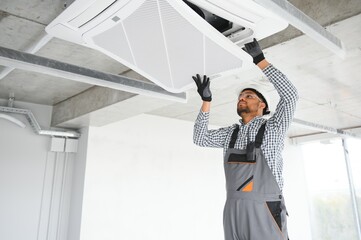 Professional technician maintaining modern air conditioner indoors. Space for text