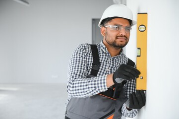 Indian construction worker with mustache uses water level measuring device