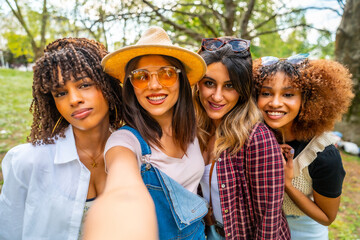 Four young women taking selfie in park